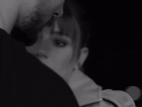 a black and white photo of a man and a woman looking into each other 's eyes