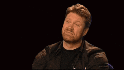 a man with a beard is wearing a black shirt and black jacket