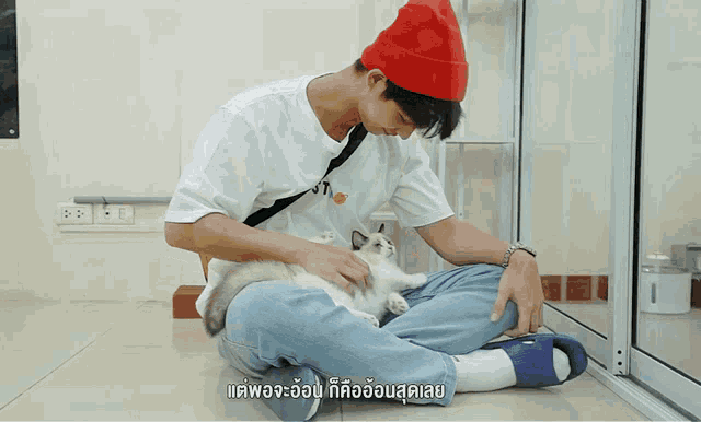 a man wearing a red hat is petting a kitten