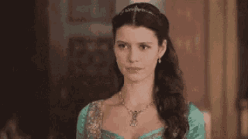 a woman wearing a tiara and a necklace is looking at the camera