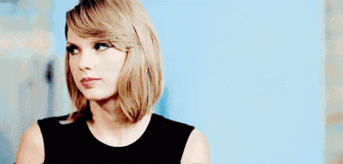 taylor swift is making a funny face while holding her hand to her eye .