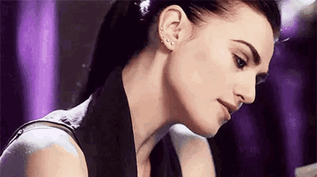 a close up of a woman 's face with a ponytail and earrings on her ears .