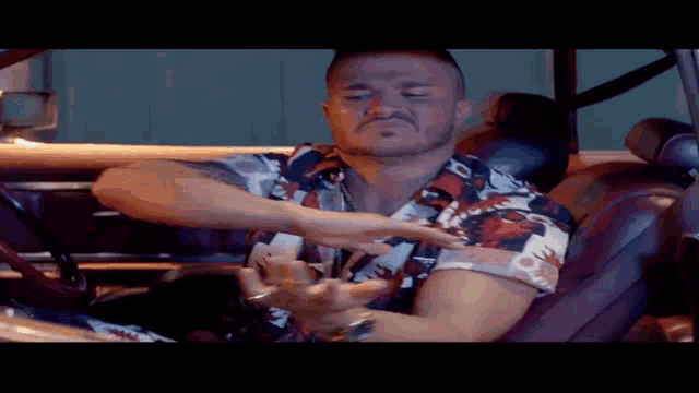 a man is sitting in the driver 's seat of a car and making a funny face .