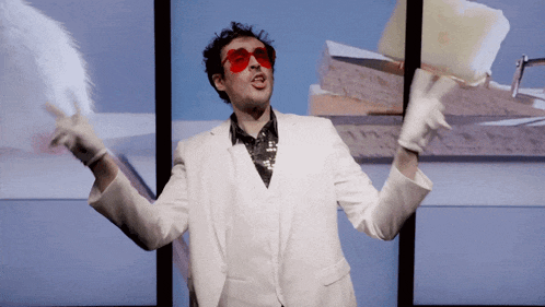 a man in a white suit and red sunglasses is holding a feather