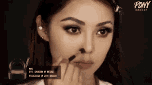 a woman is applying makeup to her face with a pony makeup product .