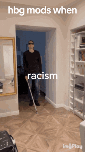 a man holding a cane in a hallway with the words hbg mods when racism on the bottom