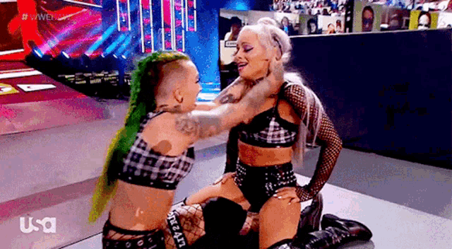 a couple of women are wrestling on a stage and one of them is holding the other 's head .