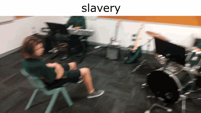 a blurry picture of a man sitting in a chair in front of a drum set with the word slavery above him