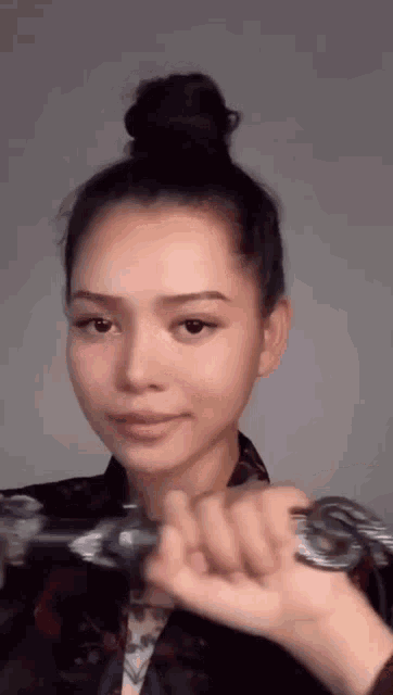 a woman with her hair in a bun is holding a sword in her hand .