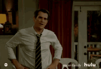 a man in a white shirt and tie is standing in a room .