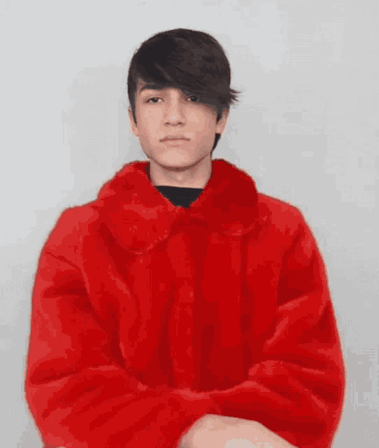 a young man wearing a red fur coat with his arms crossed .