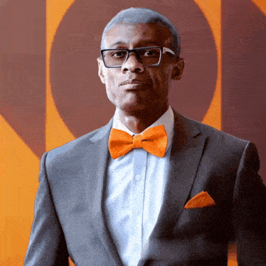 a man wearing an orange bow tie and a grey suit