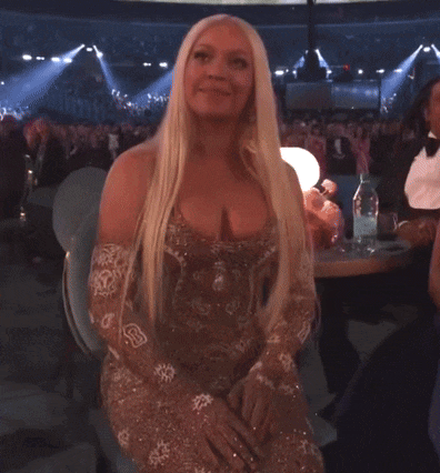 a woman with long blonde hair is sitting in front of a crowd in a stadium .