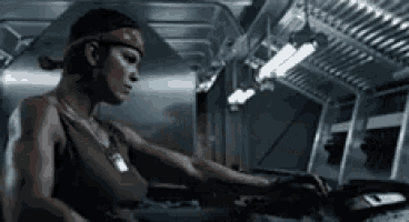 a woman wearing a bandana and a tank top is working on a machine in a dark room .