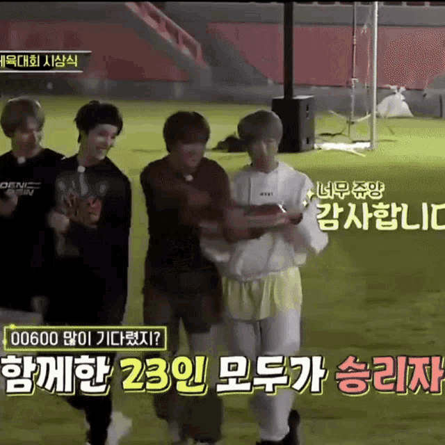 a group of young men walking on a field with korean writing on the bottom