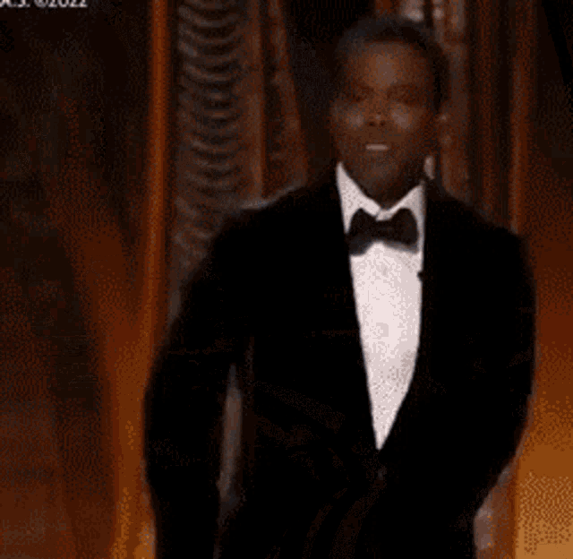 a man in a tuxedo is walking across a stage at an awards show