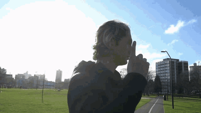 a man covering his mouth with his hand in front of a city skyline