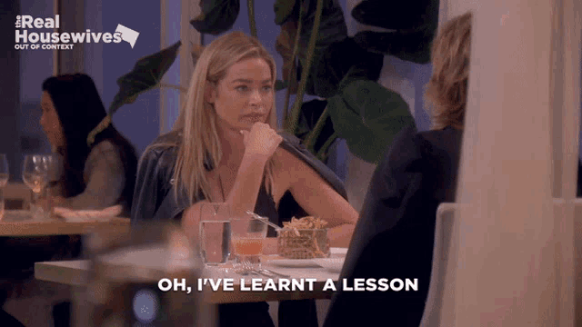 a woman sitting at a table with the words oh i 've learnt a lesson on the bottom