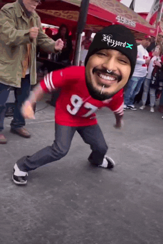 a man wearing a 49ers jersey and a beanie is dancing