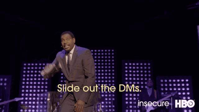 a man in a suit stands on a stage with the words slide out the dms behind him