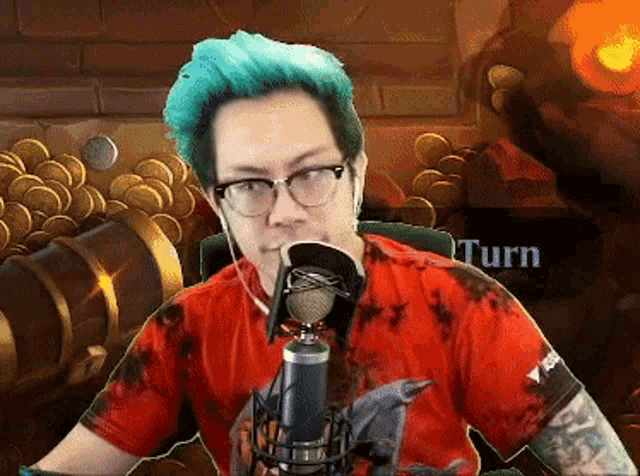 a man with blue hair and glasses is sitting in front of a microphone with the words turn behind him