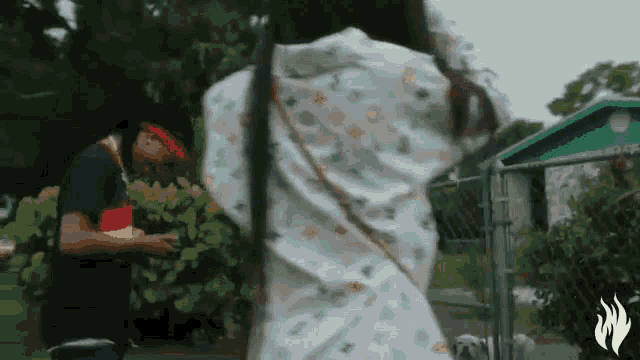 a man and a woman are standing next to each other in front of a fence and a house .