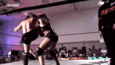 a man and a woman are wrestling in a ring with a referee watching .
