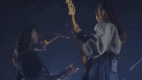 a group of women are dancing on a stage while playing guitars .