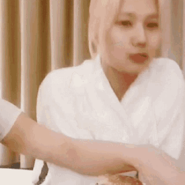 a woman in a white robe is sitting at a table with her arm around another woman 's arm .