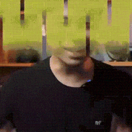 a man wearing a black shirt with the word raf on it is standing in front of a green wall .