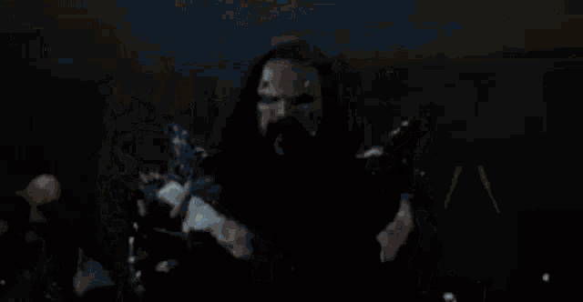 a man with long hair and a beard is standing in a room with a group of people .