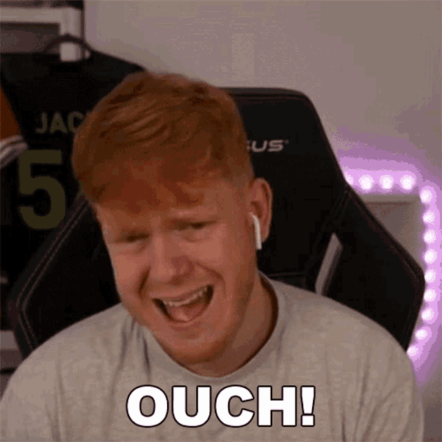 a man with red hair is sitting in a chair and making a funny face while wearing ear buds .