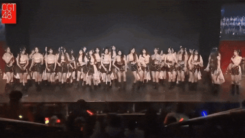 a group of women are dancing on a stage with a sign that says cct 48
