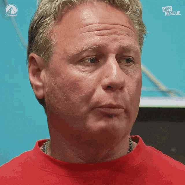 a man wearing a red shirt with the words bar rescue on it