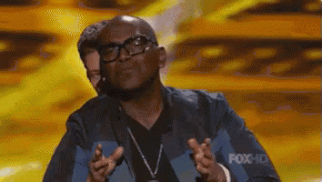 a man wearing glasses is giving a thumbs up sign on a stage .