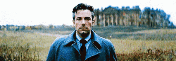 a man in a suit and tie standing in a field .