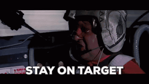 a man wearing a helmet and a microphone is sitting in a car with the words stay on target written on the screen .
