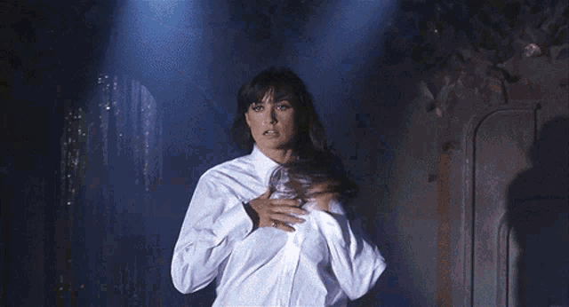 a woman is taking off her white shirt in the dark