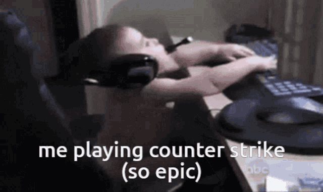 a baby wearing headphones is laying on a desk playing counter strike
