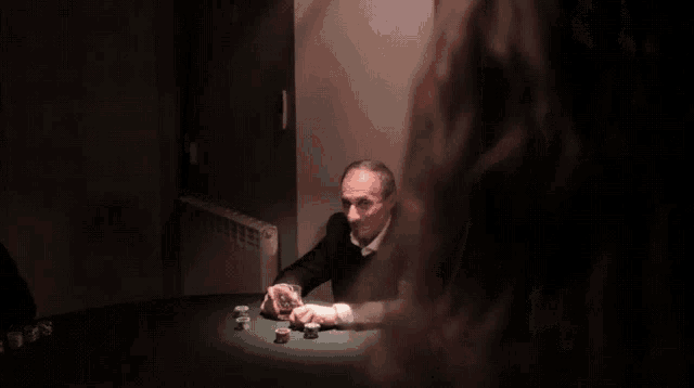 a man sitting at a table with a glass of wine and poker chips
