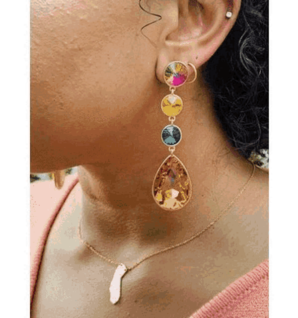 a woman wearing a pair of earrings and a necklace with multicolored stones .