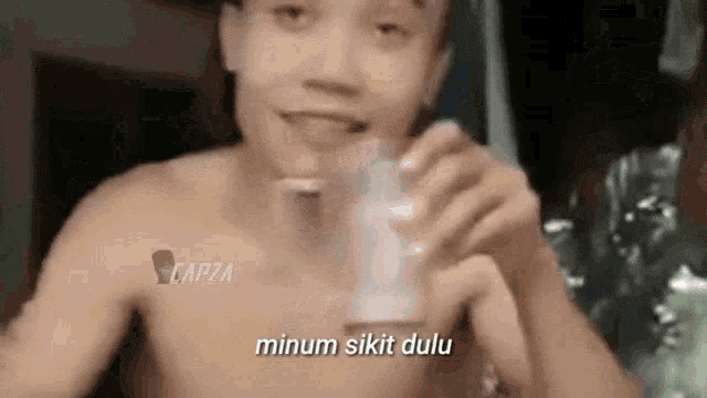 a shirtless man is drinking from a glass with the words minum sikat dulu written on the bottom .