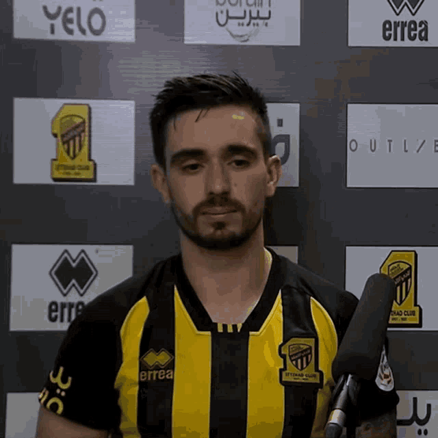 a man wearing a yellow and black striped shirt with errea written on it