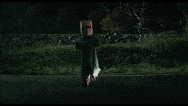 a man and a woman are standing next to each other in a dark room . the woman is wearing a pink coat .