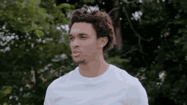 a man in a white shirt stands in front of trees