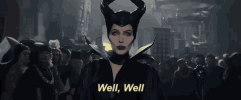a woman in a maleficent costume is standing in front of a crowd of people and says well , well .
