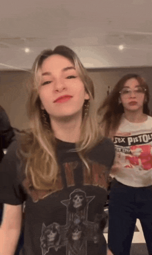 a woman wearing a shirt that says sex pistols stands next to another woman