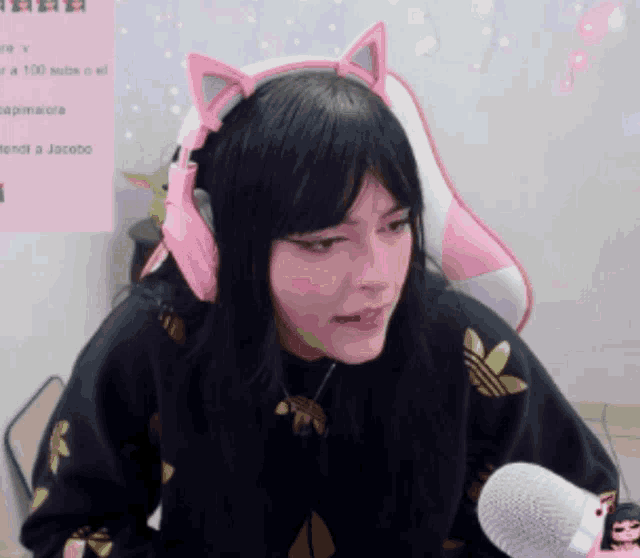 a woman wearing pink cat ear headphones and a black adidas sweatshirt