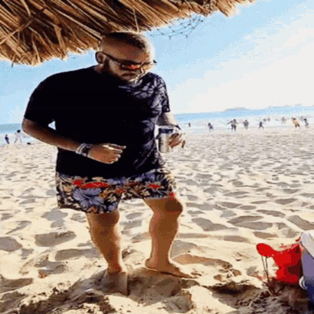 a man is standing on a beach holding a can of soda