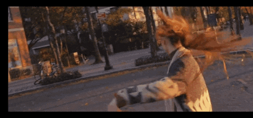 a woman with long hair is walking down a street
